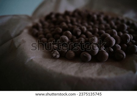 Fresh unshelled hazelnuts on brown paper. Royalty-Free Stock Photo #2375135745