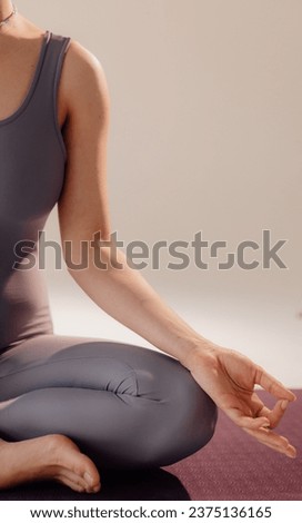 Close-up front view of woman doing yoga sitting on yoga mat. Woman doing yoga while sitting on a light background