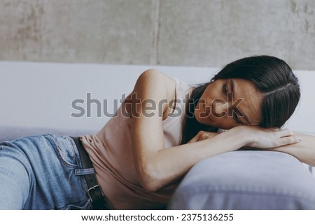 Distempered unnerved sad worried minded young latin woman 20s in casual clothes sit lay on sofa think plan hands folded under head spend time in living room home in own house. People emotions concept Royalty-Free Stock Photo #2375136255