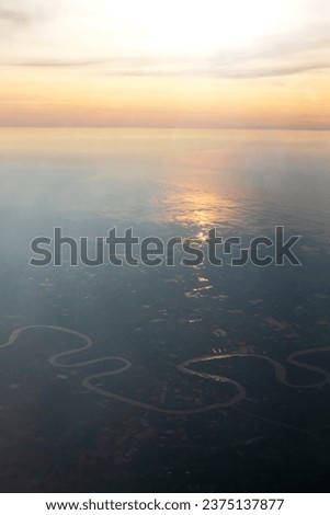 Beautiful airplane view to the sunset sky over the sea. Reflection on water background is highlighted by sun rays.