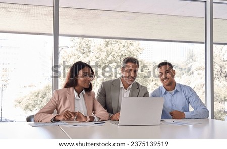 Three business people workers using laptop working in office. Older male executive manager and professional international workers team looking at computer discussing tech project at work meeting. Royalty-Free Stock Photo #2375139519