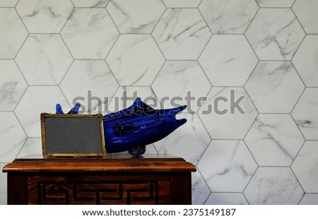 empty picture golden frame mockup and blue glass fish on wooden table. Elegant working space, home office concept. interior design 