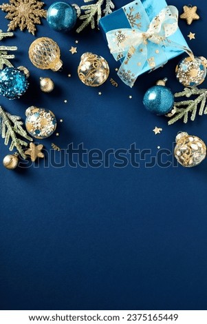 Blue and gold luxury Christmas balls ornaments, glitter blue paper gift box, fir branches on dark blue background. Xmas vertical banner design, Happy New Year party invitation card template.