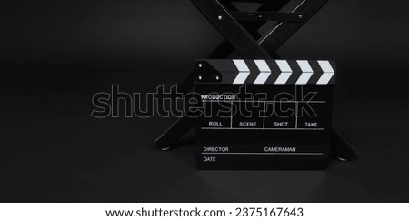 Black clapper board or movie slate with director chair on black background.
