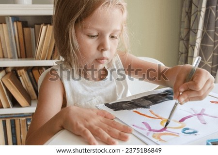 Little child draws with watercolor, concept of education in the kindergarten, soft focus background