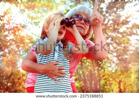 Little girl with her grandmother looking through binoculars outdoor. Discovery, adventure, having fun time with family. Birdwatching Royalty-Free Stock Photo #2375188851