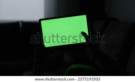 Man at home lying on a couch with tablet pc with green screen