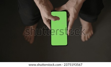 POV top view shot of man use phone with green screen indoor sitting on a couch