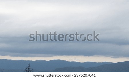 Autumn brings overcast skies adorned with gray stratus clouds, hinting at impending rain. This full-screen view provides ample space for text or design elements, making it perfect for various projects Royalty-Free Stock Photo #2375207041