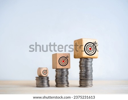 Target icons on wooden cube blocks expanding on coin stack bar graph steps on white background. Investment, profit, income, sales, business goal, growth and success, economic improvement concepts.