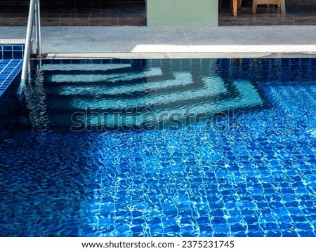 Swimming pool steps with clear water surface background, nobody. Abstract pool texture, underwater pattern blue background with grab bar ladder, no people. Summer background.