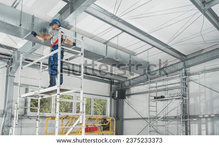 Professional HVAC Worker on a Scaffolding Installing Air Duct Royalty-Free Stock Photo #2375233373