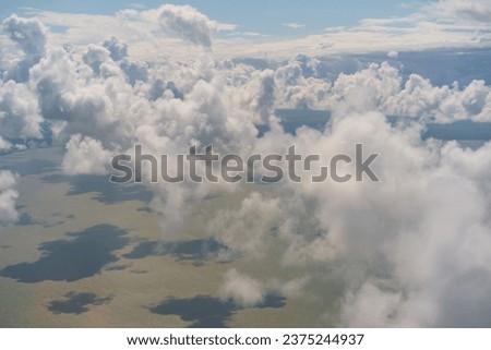 Photography of blue sky with white clouds. Beautiful view through the aircraft window. Concepts of the beauty in nature, freedom and travel mood.  The green earth is visible below. Kaliningrad region