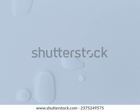 water droplets on a white surface. The droplets are clear, spherical shapes with reflections of the surface below. The reflections give the droplets depth and life.