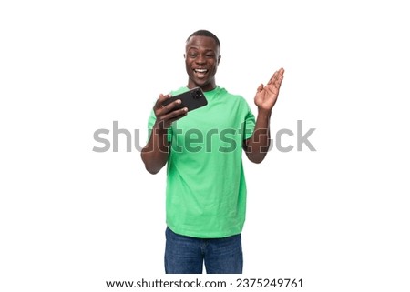 A 30-year-old American man dressed in a light green basic T-shirt is watching a video on a smartphone