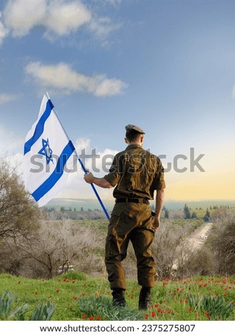 Israeli soldier with Israel flag against the sunset in the blooming desert. Concept - armed forces of Israel. Royalty-Free Stock Photo #2375275807
