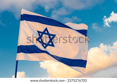 The flag of Israel on a field and a cloudy sky background. Memorial day-Yom Hazikaron, Patriotic holiday Independence day Israel - Yom Ha'atzmaut concept. Royalty-Free Stock Photo #2375276703