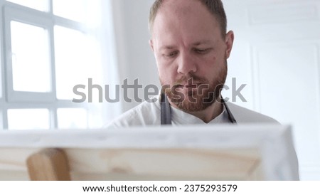Portrait of an artist working on an abstract painting, using a brush to create a modern painting