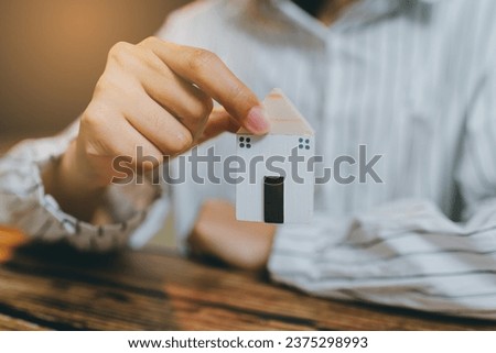 Hand holding a wooden house model.