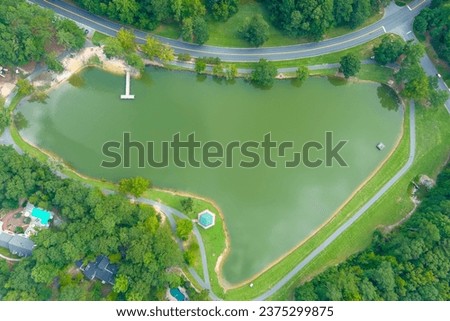 an overhead aerial shot of a gorgeous summer landscape at Huddleston Pond Park with a lake surrounded by lush green trees, grass and plants in Peachtree City Georgia USA