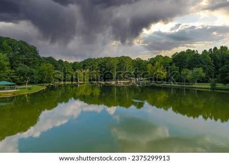 a stunning aerial shot of the silky green waters of the lake with vast miles of lush green trees and powerful clouds and birds on the lake at Huddleston Pond Park in Peachtree City Georgia USA