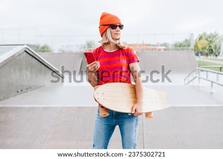 Portrait Of Skater Girl In Skatepark. Female hipster woman In Casual Outfit standing with Skateboard on summer day. Active lifestyle, modern life, subculture concept