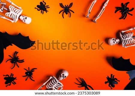 Halloween and decoration concept - orange background with spiders, bats, skeletons. Flat lay, top view. Place for your text.