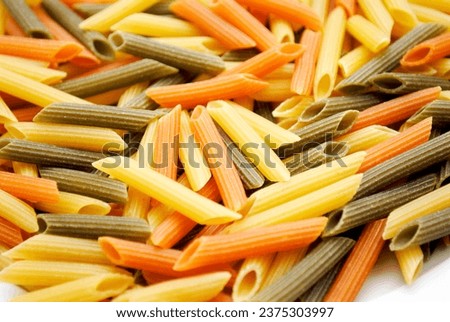 Closeup of Raw Cylinder-shaped Penne Pasta Noodles in Three Colors Yellow, Green and Red	 Royalty-Free Stock Photo #2375303997