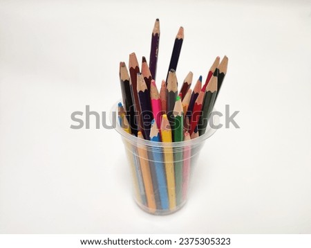 Irregular long and short colored pencils in a glass, isolated on a white background