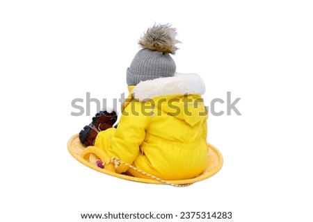 Happy toddler baby rides on an ice sled in the snow in a yellow snowsuit, isolated on white background. Child boy in warm clothes walks in winter park. Kid aged one year six months Royalty-Free Stock Photo #2375314283