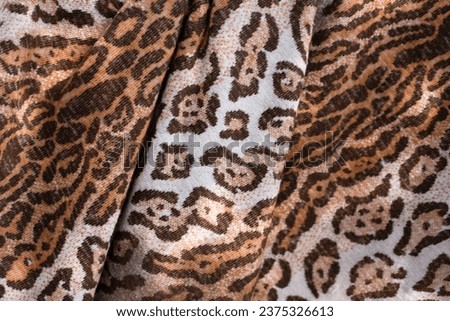 Wavy textured fabric with leopard or cheetah print, close up. The fabric is made as an imitation of the skin of a wild leopard