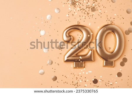 Gold candles in the form of number twenty on peach background with confetti. 20 years anniversary celebration. Royalty-Free Stock Photo #2375330765