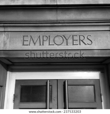 Black and white image of an office building entrance with the word Employers carved in stone above the doorway. 