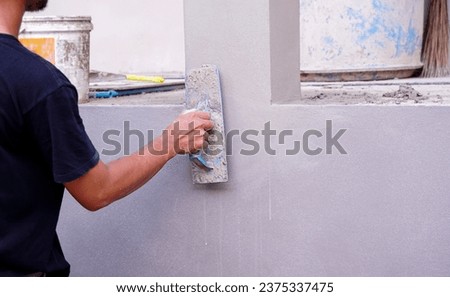 Hands of worker plasterer pillar cement construction with trowel, man at work by plastering a wall of construction site.Home renovation and building new house. Royalty-Free Stock Photo #2375337475