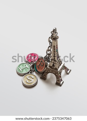 The little Eiffel Tower is a souvenir keychain, as a keepsake, from Paris on a light background