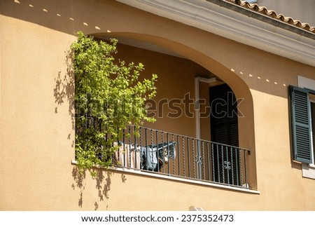 rchitectural elements of a typical Spanish small-town balcony. Laundry dries on the balcony, with semicircular arches and green shutters overlooking the street
