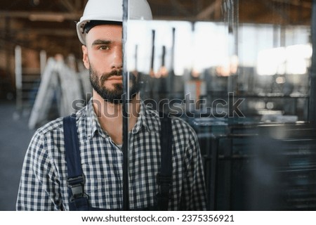 The glazier carries the glass in the glass factory Royalty-Free Stock Photo #2375356921