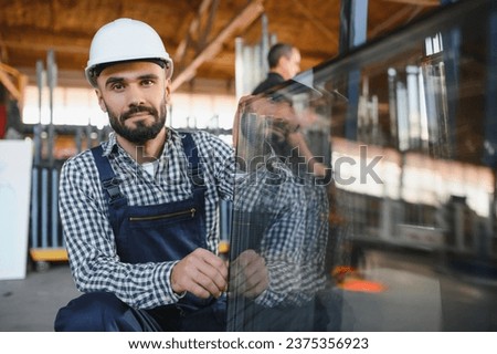The glazier carries the glass in the glass factory Royalty-Free Stock Photo #2375356923