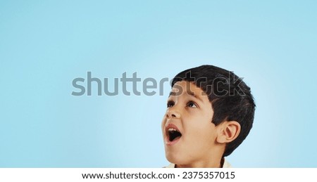 Surprise, boy and child with decision, opportunity and fantasy on a blue studio background. Person, mockup space and happy kid looking up, future and announcement with shock, expression and emoji