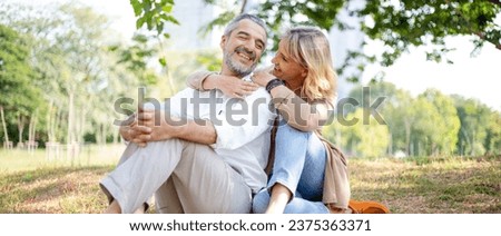 Senior elderly Caucasian couple sitting on ground together in park, wife talking with husband, Love life goals, Beautiful old retired people activity in autumn, concept for lifestyle insurance Royalty-Free Stock Photo #2375363371