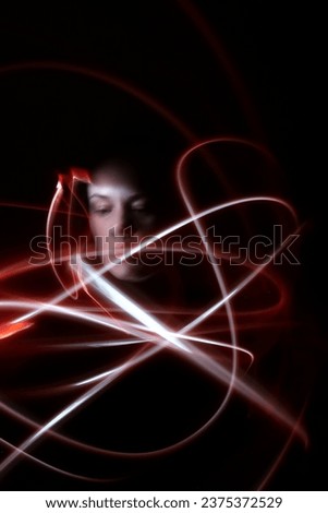 Abstract red lights, white tones, dark background, abstract shapes, luminous lines in darkness, blurry face of a woman, long exposure photography, moving fine lines