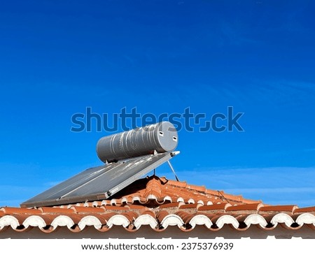 Solar water heater installed on tile roof of house for environmentally friendly heating of water. Algarve, Portugal. Horizontal photo. 