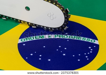 Brazil flag and chainsaw. Deforestation, rainforest destruction and climate change concept. Royalty-Free Stock Photo #2375378301