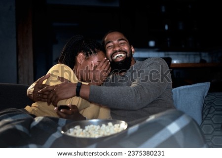 African American couple watching a movie at home over a streaming cable service. Movie night. Woman is very emotional
