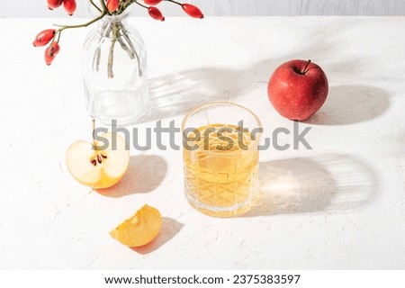 Fresh ripe apples and glass of apple juice or cider on white table in sunlight. Autumn harvest, Thanksgiving concept. Top view. Royalty-Free Stock Photo #2375383597