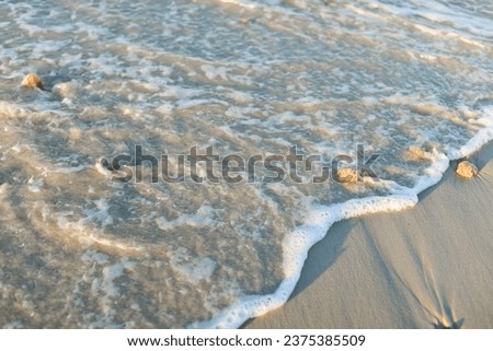 Waves gently kiss the sandy shore as people relax, capturing the serenity and joy of seaside vacations Royalty-Free Stock Photo #2375385509