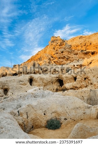 Towering limestone cliffs with lots of caves rise up from a stormy sea. Algar Seco, Carvoeiro in southern Portugal , Algarve. Reef formation from sandstone on the coast. Vertical photo. 
