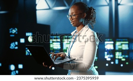 Focused IT consultant strolling through server rows providing processing resources for different workloads. Competent inspector overseeing supercomputers tasked with solving complex operations Royalty-Free Stock Photo #2375395959