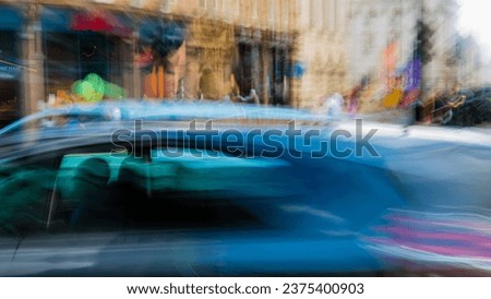 Abstract motion blurred image of a blue car on a central London street with the driver in silhouette
