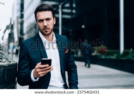 Serious businessman using smartphone on street